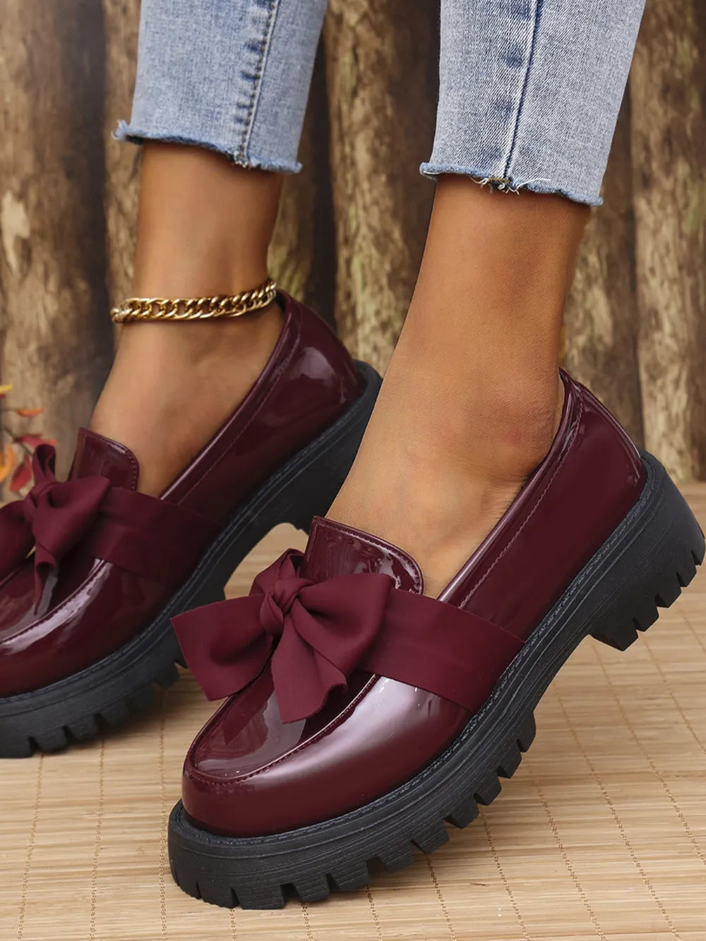 Burgundy patent platform loafers with bow detail and chunky sole.