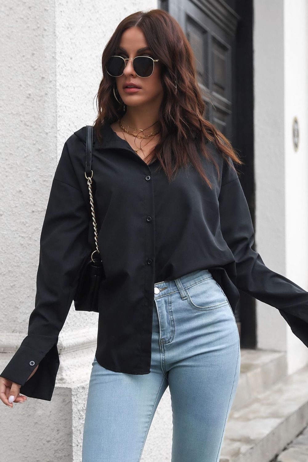 Oversized black cotton poplin shirt with button front and split cuffs, styled casually.