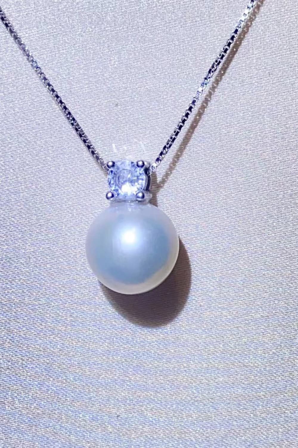 Solitaire pearl pendant necklace in silver with a cubic zirconia accent on a sterling silver chain.