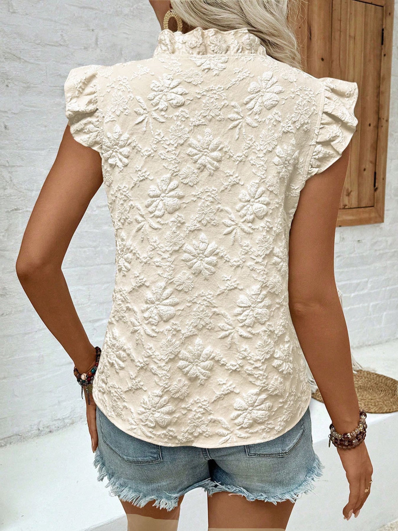 Beige floral embossed ruffle blouse with short sleeves and mock neck.