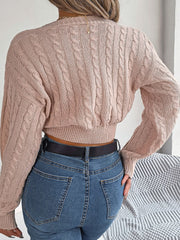 Blush pink acrylic cable knit cropped sweater with twist front detail.