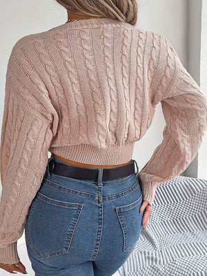 Blush pink acrylic cable knit cropped sweater with twist front detail.