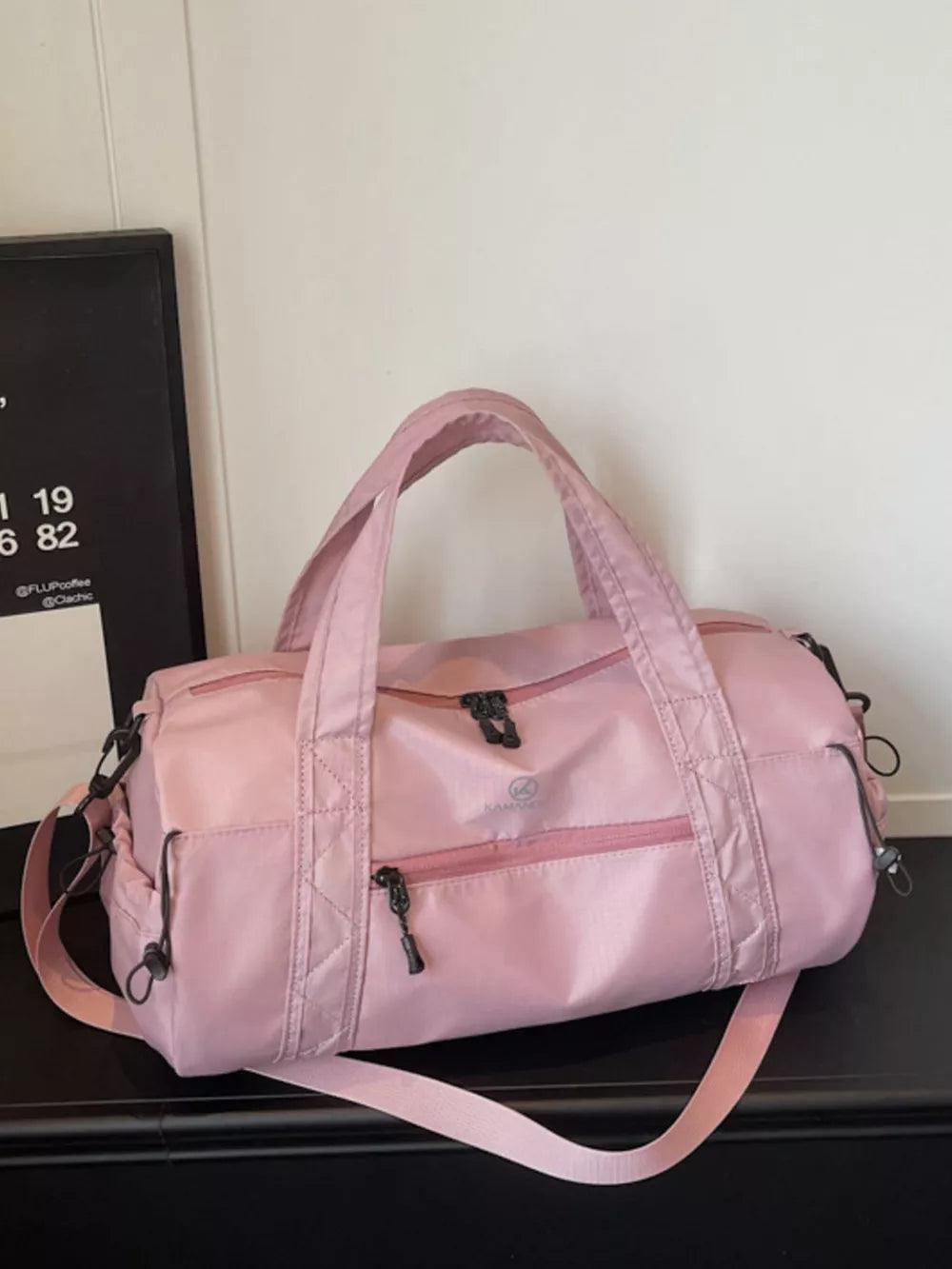 Pink nylon travel bag with multiple zippered pockets and adjustable strap.