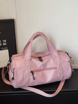 Pink nylon travel bag with multiple zippered pockets and adjustable strap.