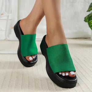 Green platform knit slide sandals with black soles and open toes.