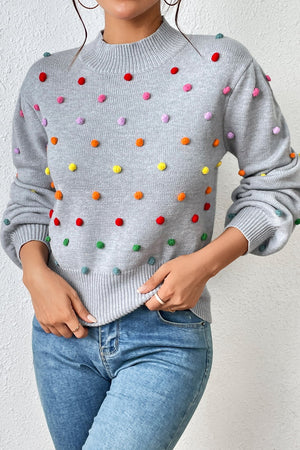 Light gray blouson knit sweater with colorful pom-pom embellishments and mock neck.