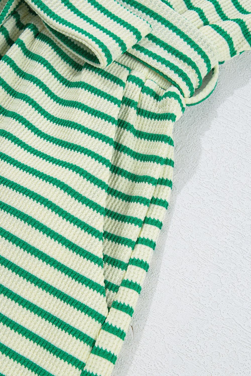 Green striped resort shirt romper with tie detail and textured fabric.
