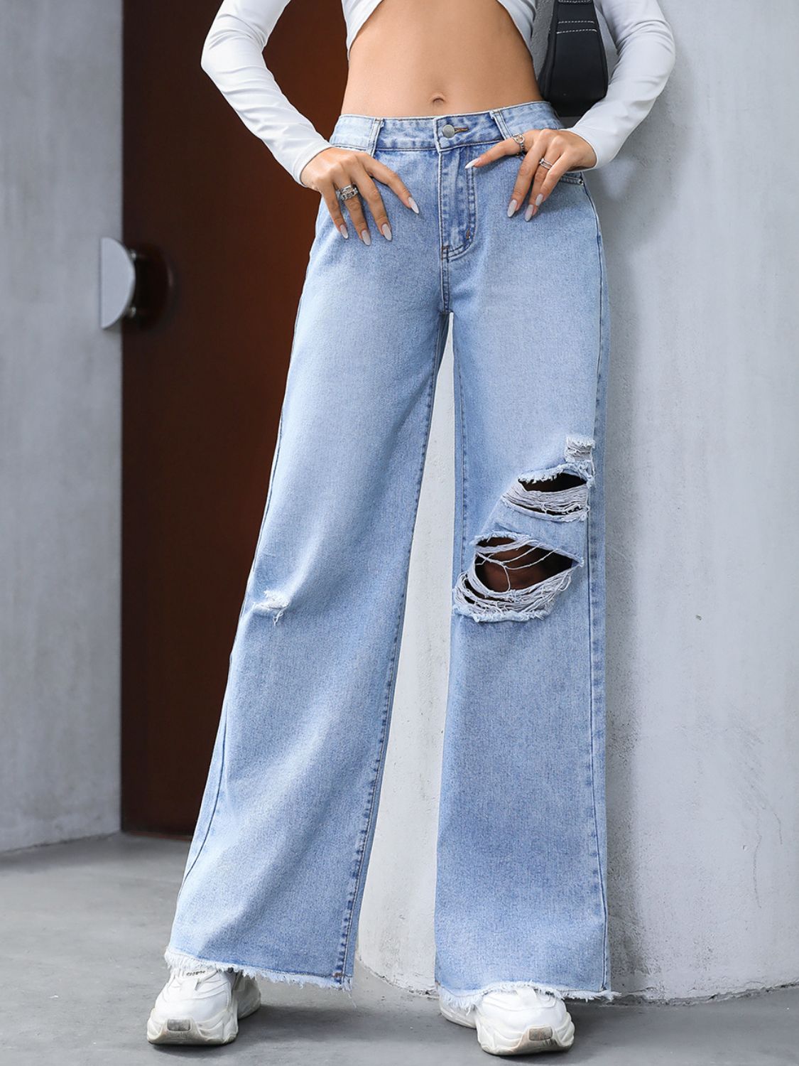 Light wash distressed wide-leg jeans with fray hem and ripped details.