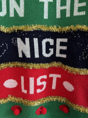 Green acrylic crewneck sweater with "Nice List" graphic and gold tinsel trim.