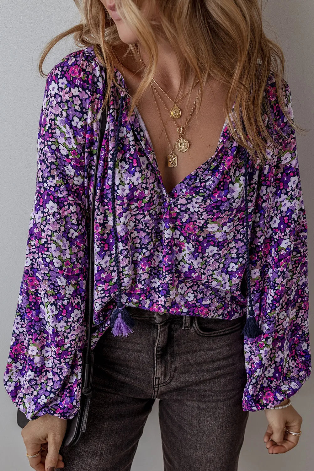Floral print blouse in electric purple with blouson sleeves and tassel details.