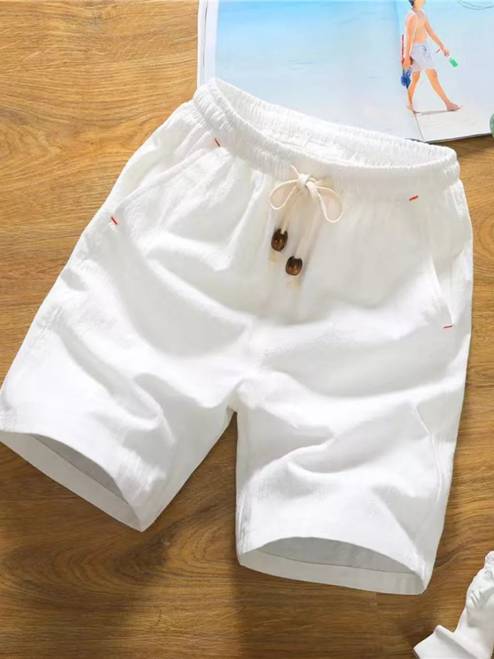 White relaxed fit chino shorts with drawstring and wooden button details.