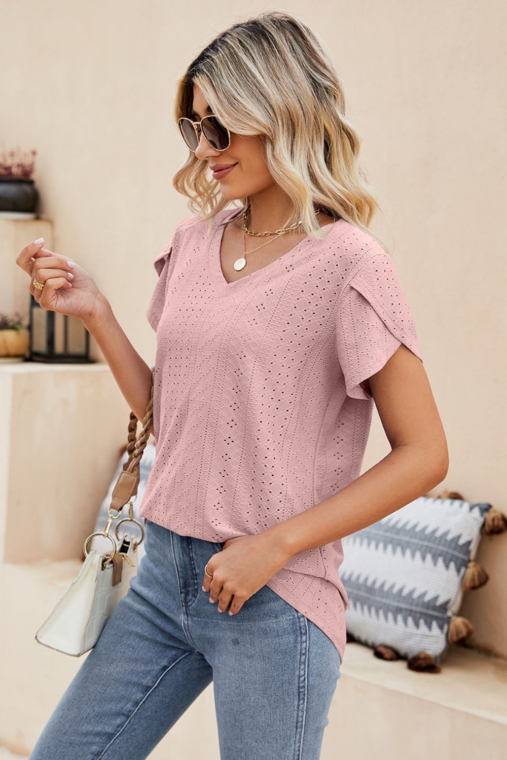 Blush pink knit top with perforated sleeve detail and V-neck.