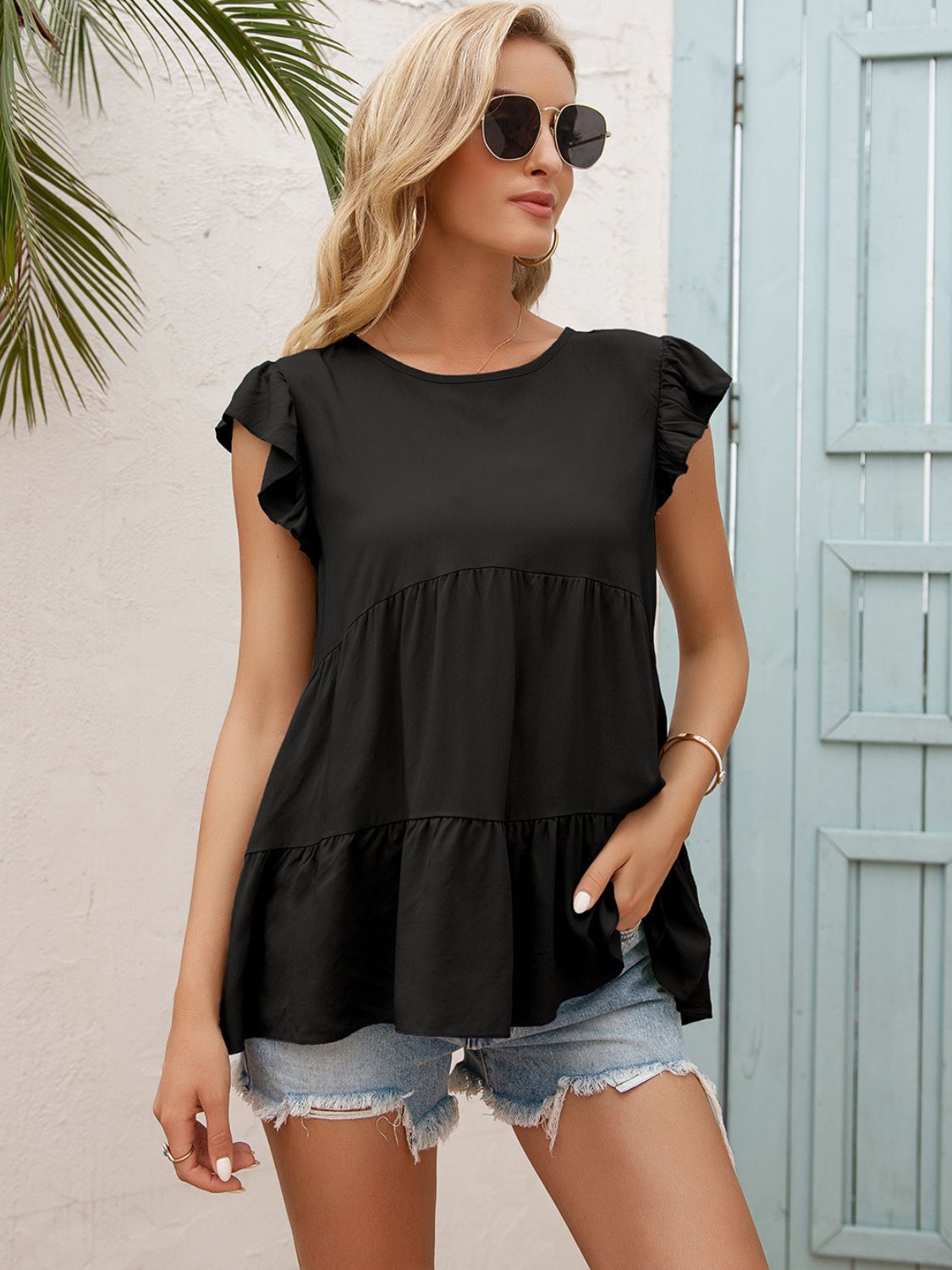 Black babydoll blouse with ruffled cap sleeves and tiered hem.