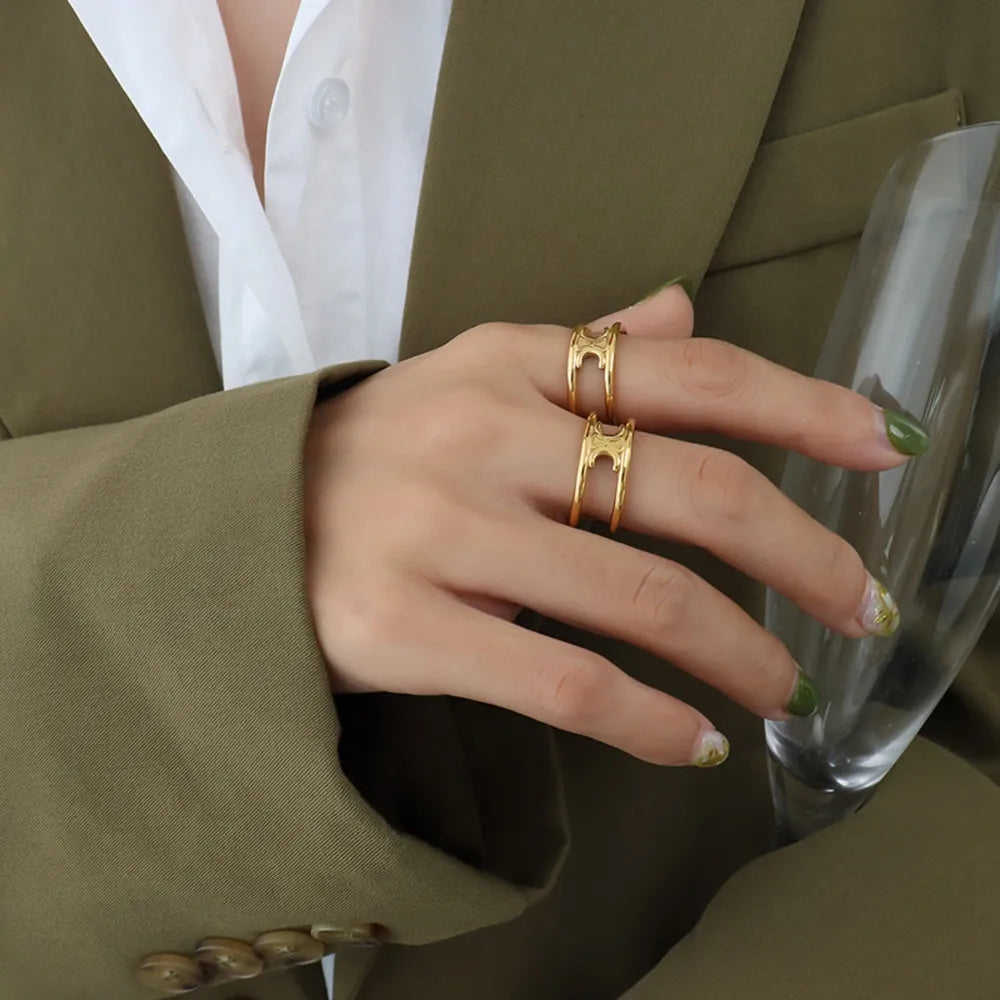 Gold double banded open ring with cutout detail, worn on a woman's hand.
