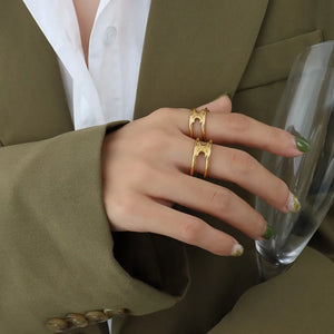 Gold double banded open ring with cutout detail, worn on a woman's hand.