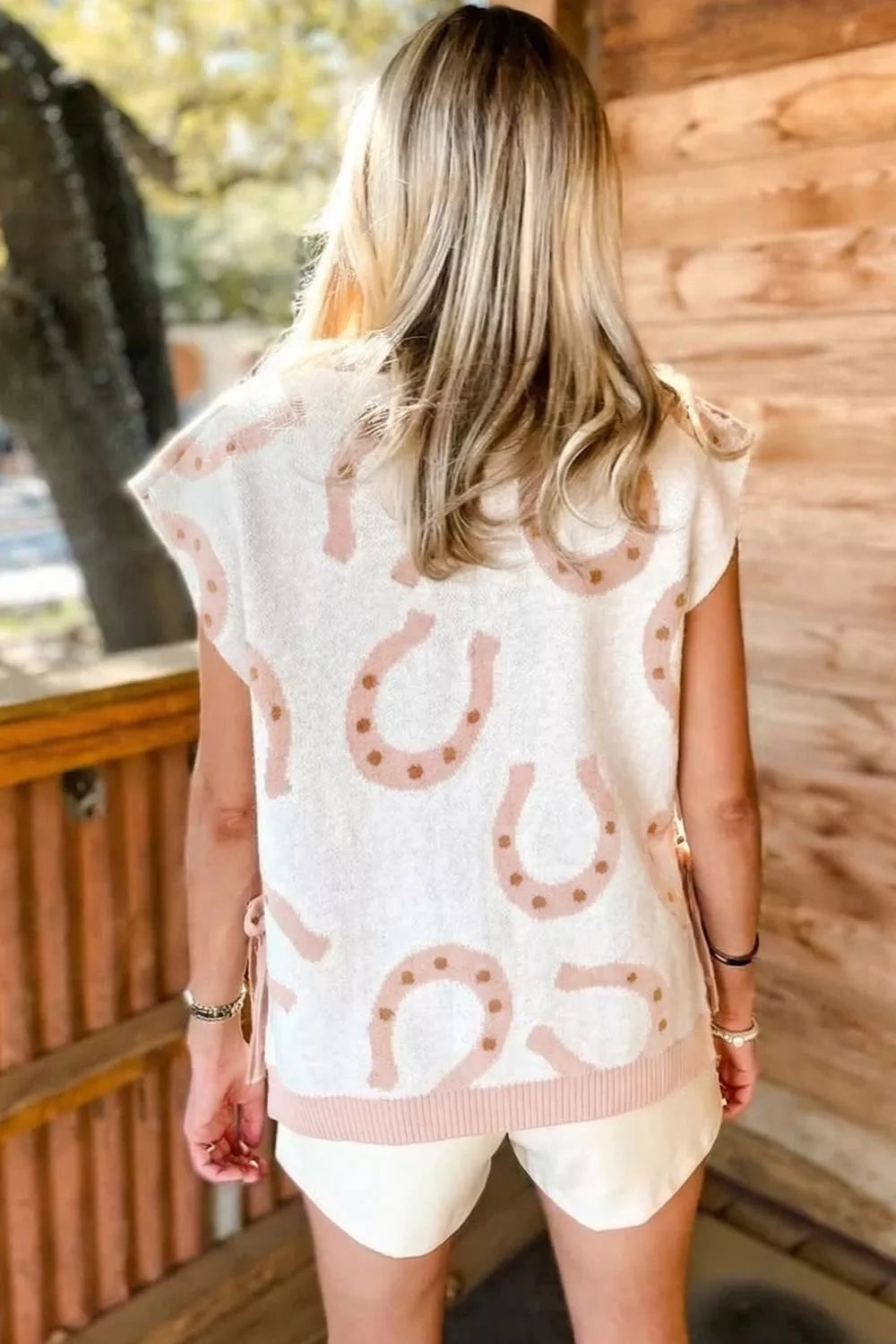 White knit tank top with pink horseshoe pattern and side ties.
