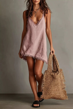 Dusty pink cotton cami dress with V-neck and fringe trim, styled with a straw bag.