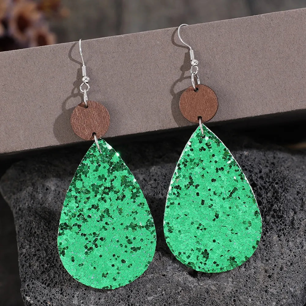 Green glitter teardrop earrings with wood accent detail.
