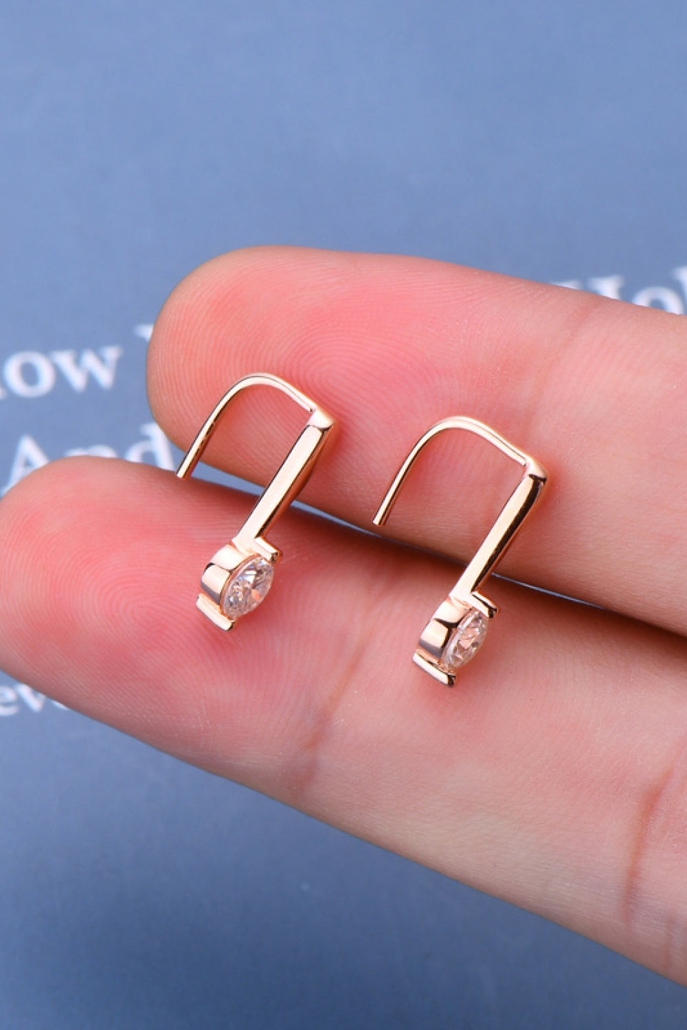 Rose gold moissanite hook earrings with a single round diamond accent.