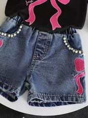 Baby denim shorts with pearl trim and pink bowknot embroidery, paired with a black tee.