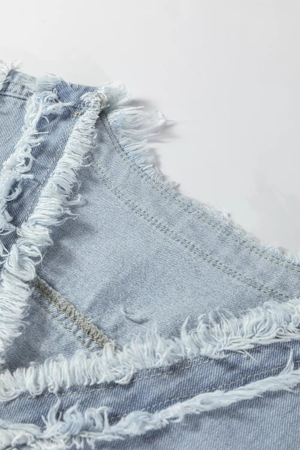 Light wash denim vest with frayed edges and visible stitching details.