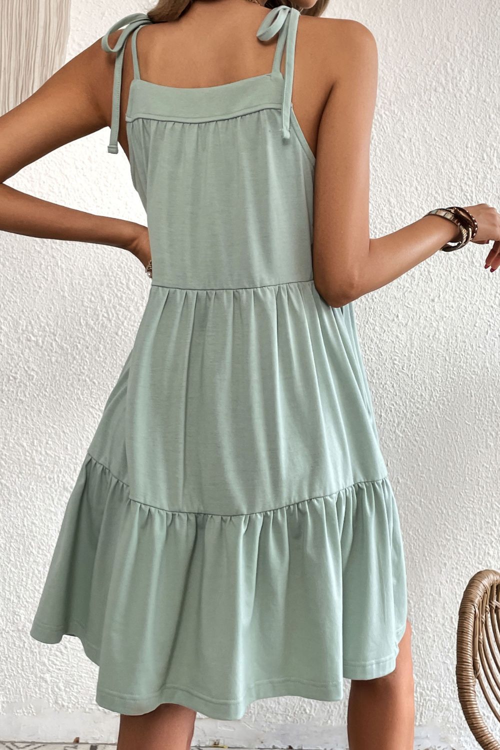 Light green tie-strap mini dress with tiered ruffle hem and square neckline.