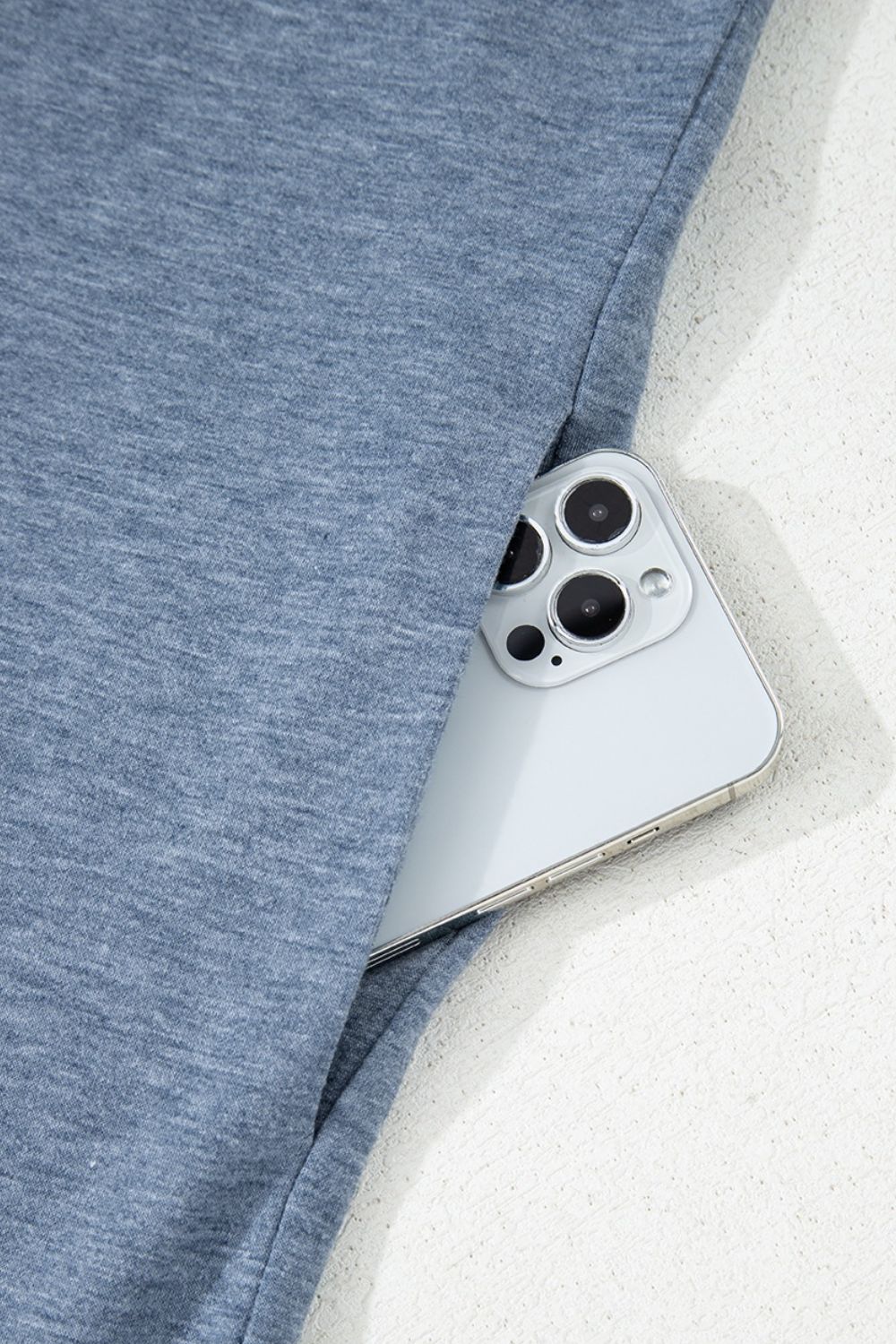 Denim-trimmed wide-leg jumpsuit in dusty blue showing a phone in the pocket