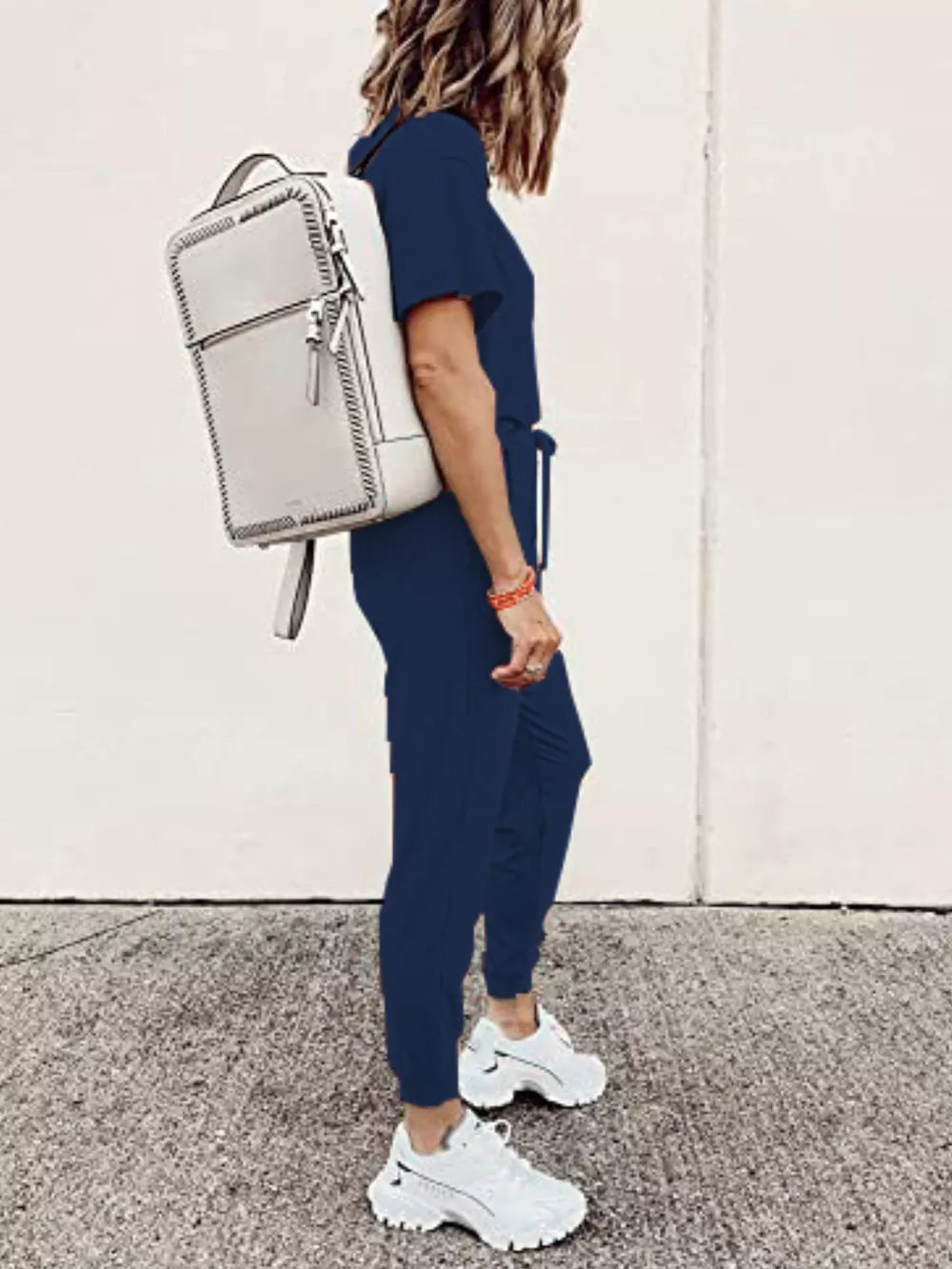 Navy blue casual round neck top and jogger pants set with drawstring waist, worn with white sneakers and a backpack.