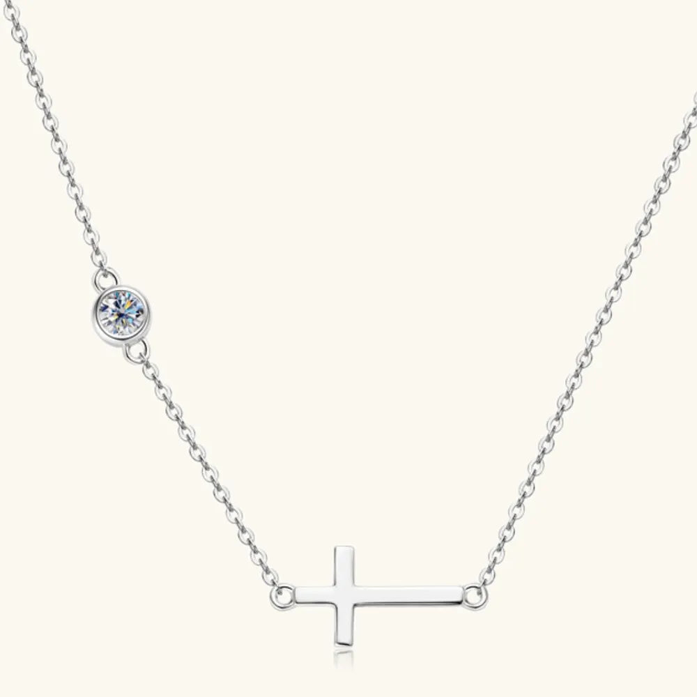 Silver asymmetrical cross pendant necklace with a single clear stone accent.