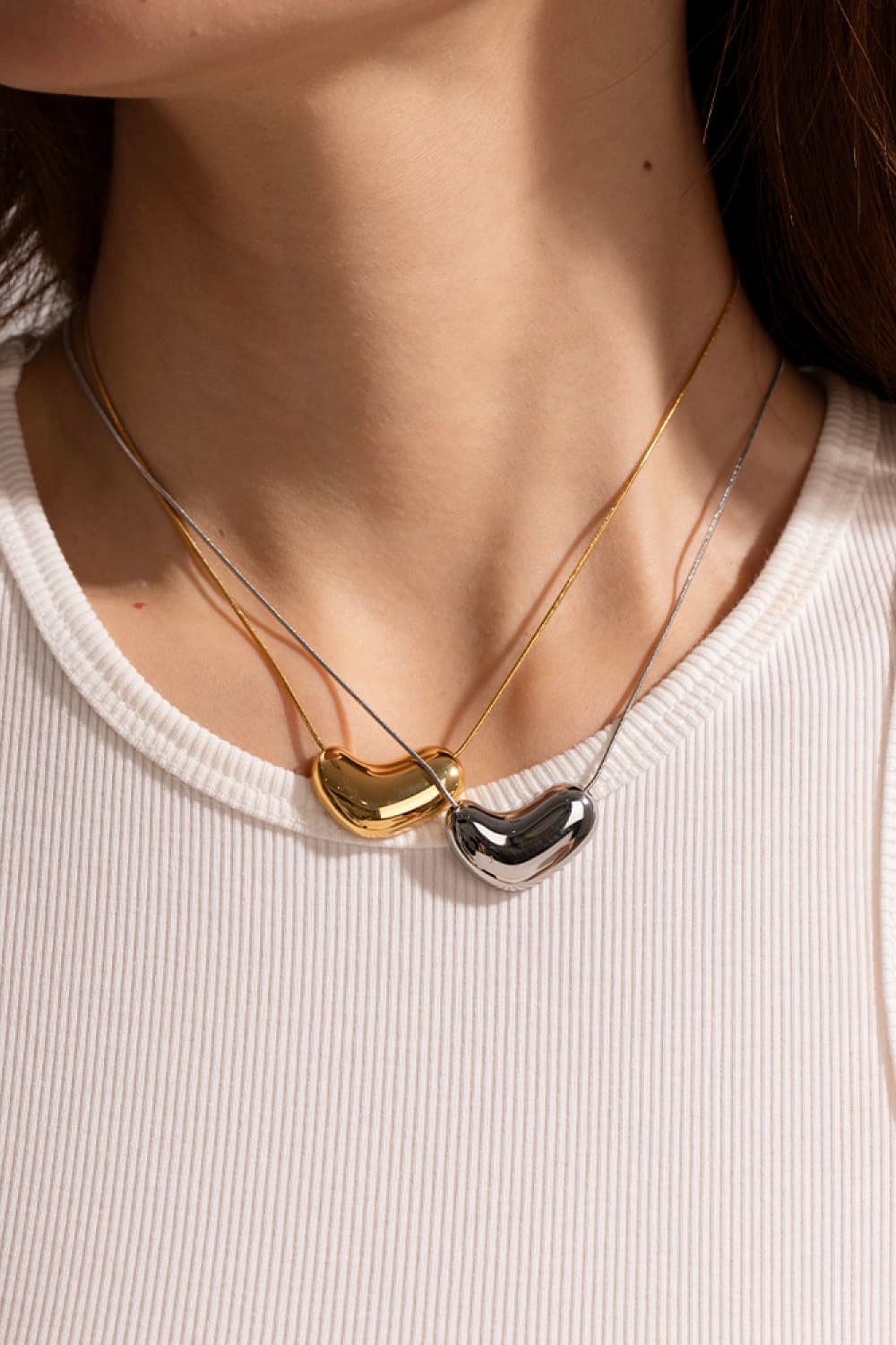 Bean-shaped sculptural pendant necklaces in gold and silver on delicate chains.