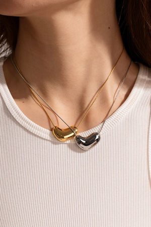 Bean-shaped sculptural pendant necklaces in gold and silver on delicate chains.