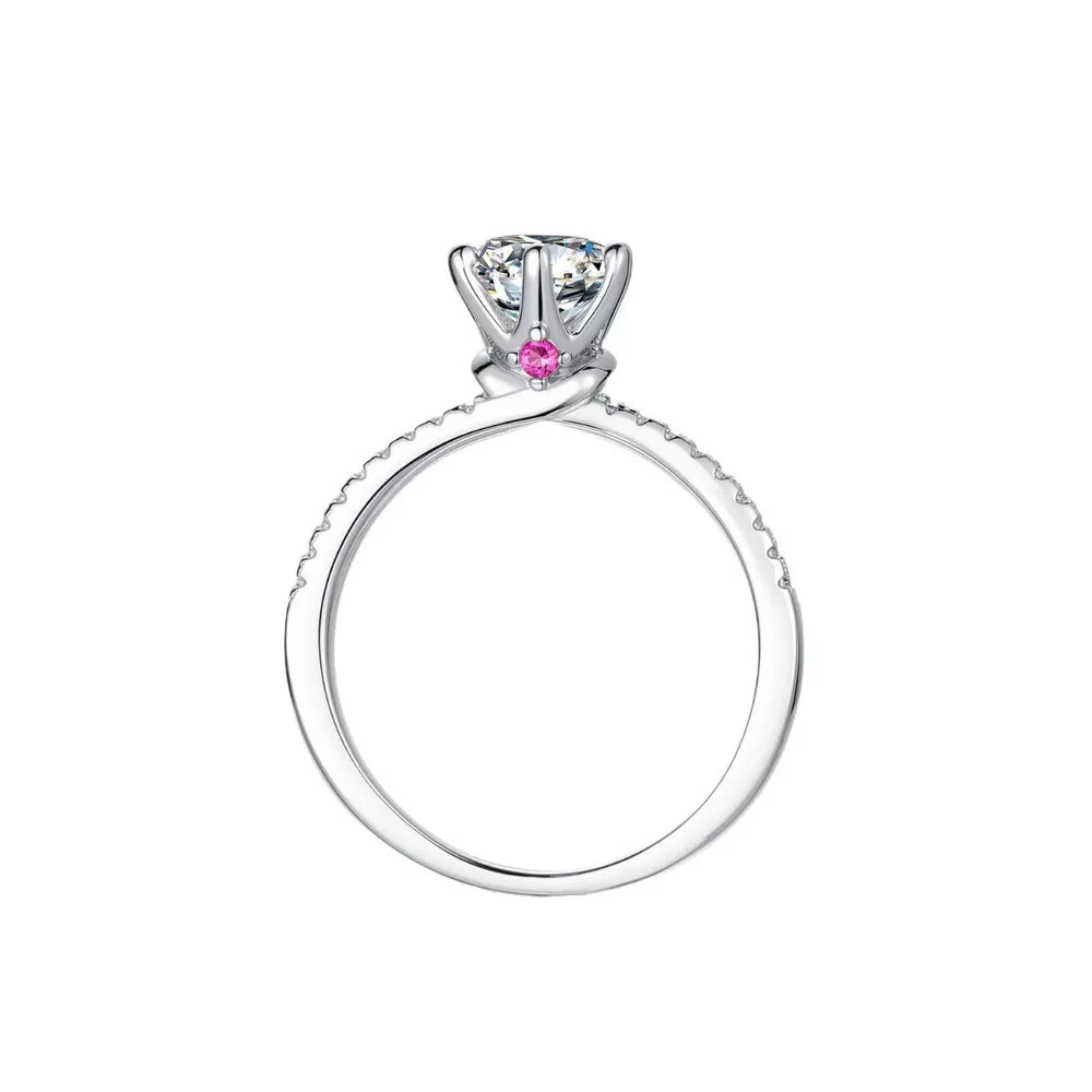 Sterling silver ring with a round moissanite and small pink accent stones on the band.