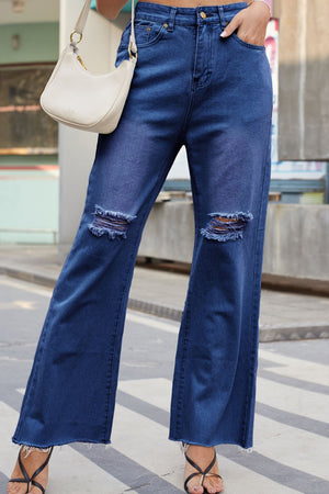 Dark wash denim flare jeans with distressed knees and frayed hem.