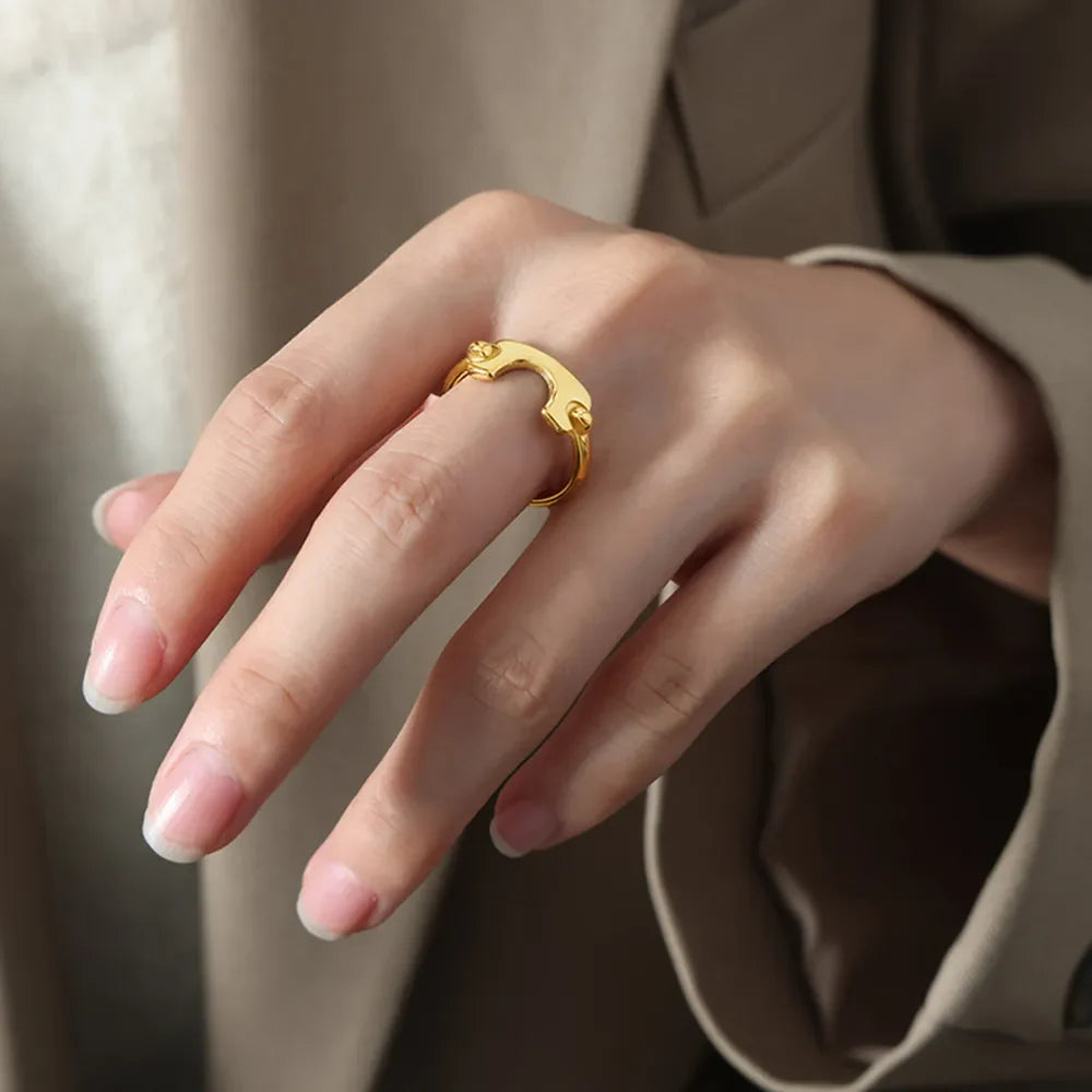 Gold open-ended ring with sculptural detail on a woman's hand