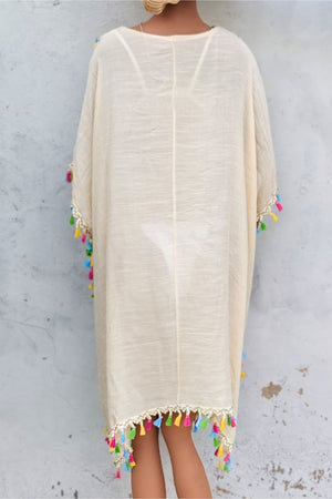 Beige kaftan dress with crochet yoke and colorful tassel trim.