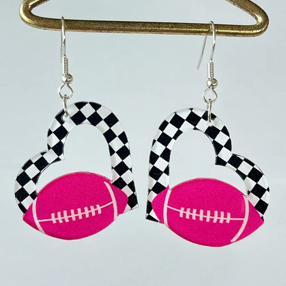 Heart-shaped acrylic earrings with pink football and black and white checkerboard pattern.
