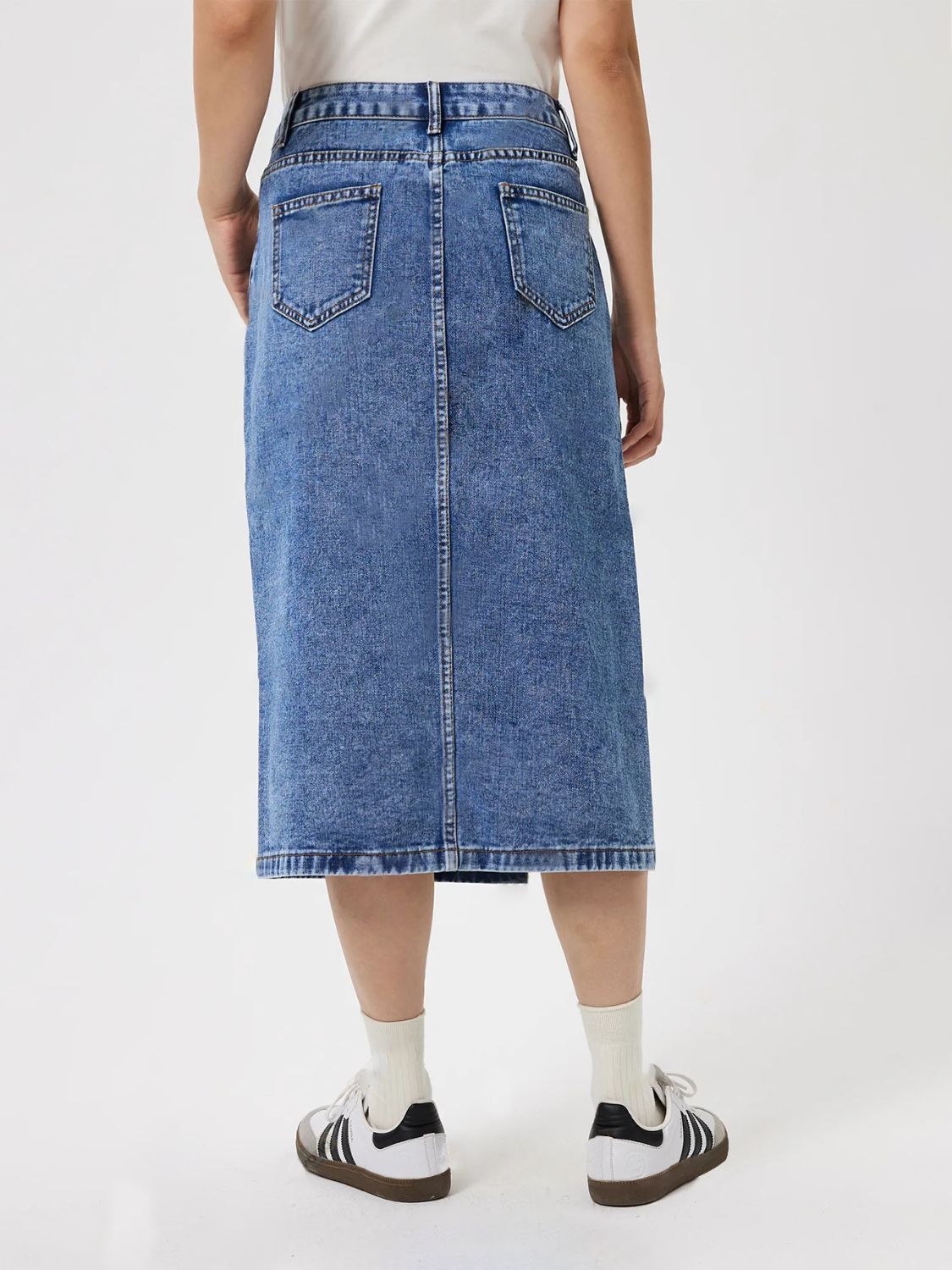 High-slit denim midi skirt in medium wash cotton with back pockets and a raw hem.