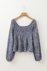Daisy print smocked peplum blouse in dusty blue with square neckline and long sleeves.