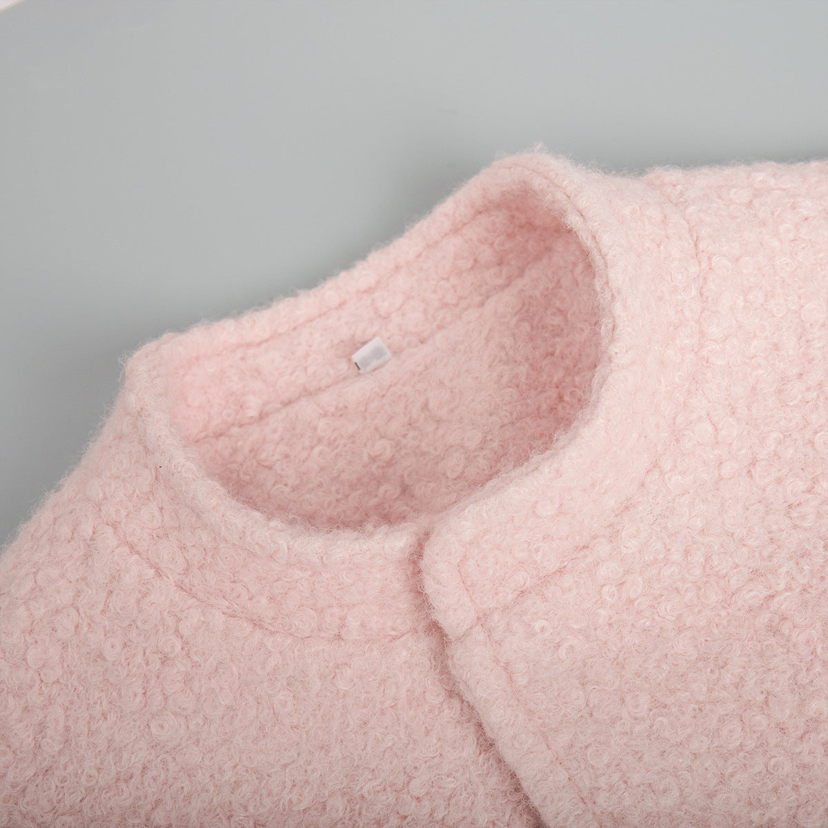 Blush pink textured bouclé bomber jacket with rounded neckline detail
