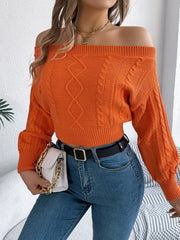 Orange cable knit off-shoulder crop sweater with diamond and braid patterns.