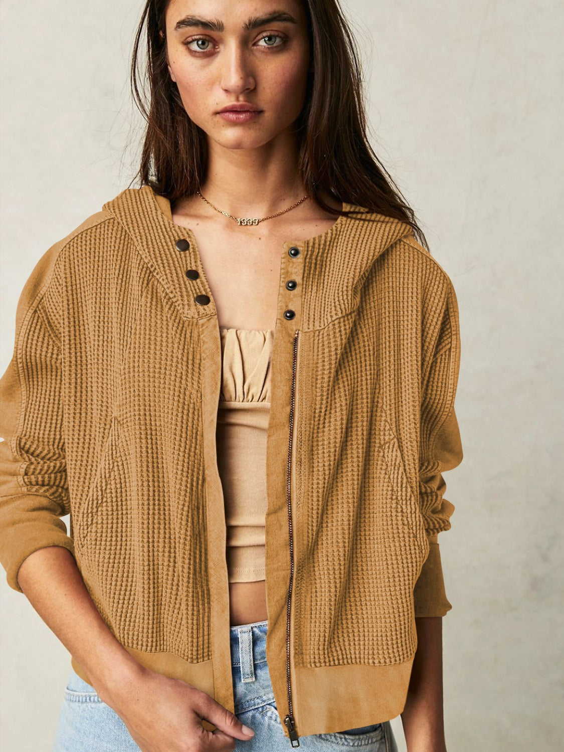 Camel waffle knit cropped hoodie with snap-front detail and zipper closure.