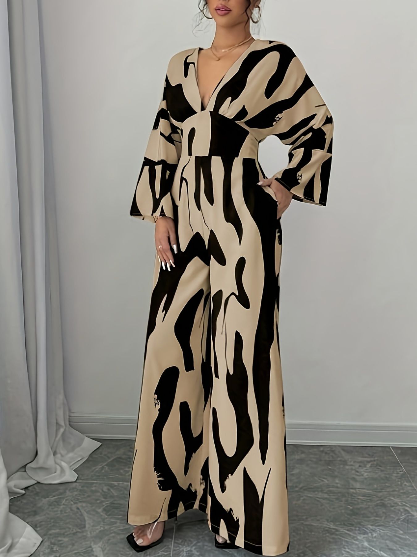 Women's abstract print wide leg jumpsuit with V-neck and bell sleeves.