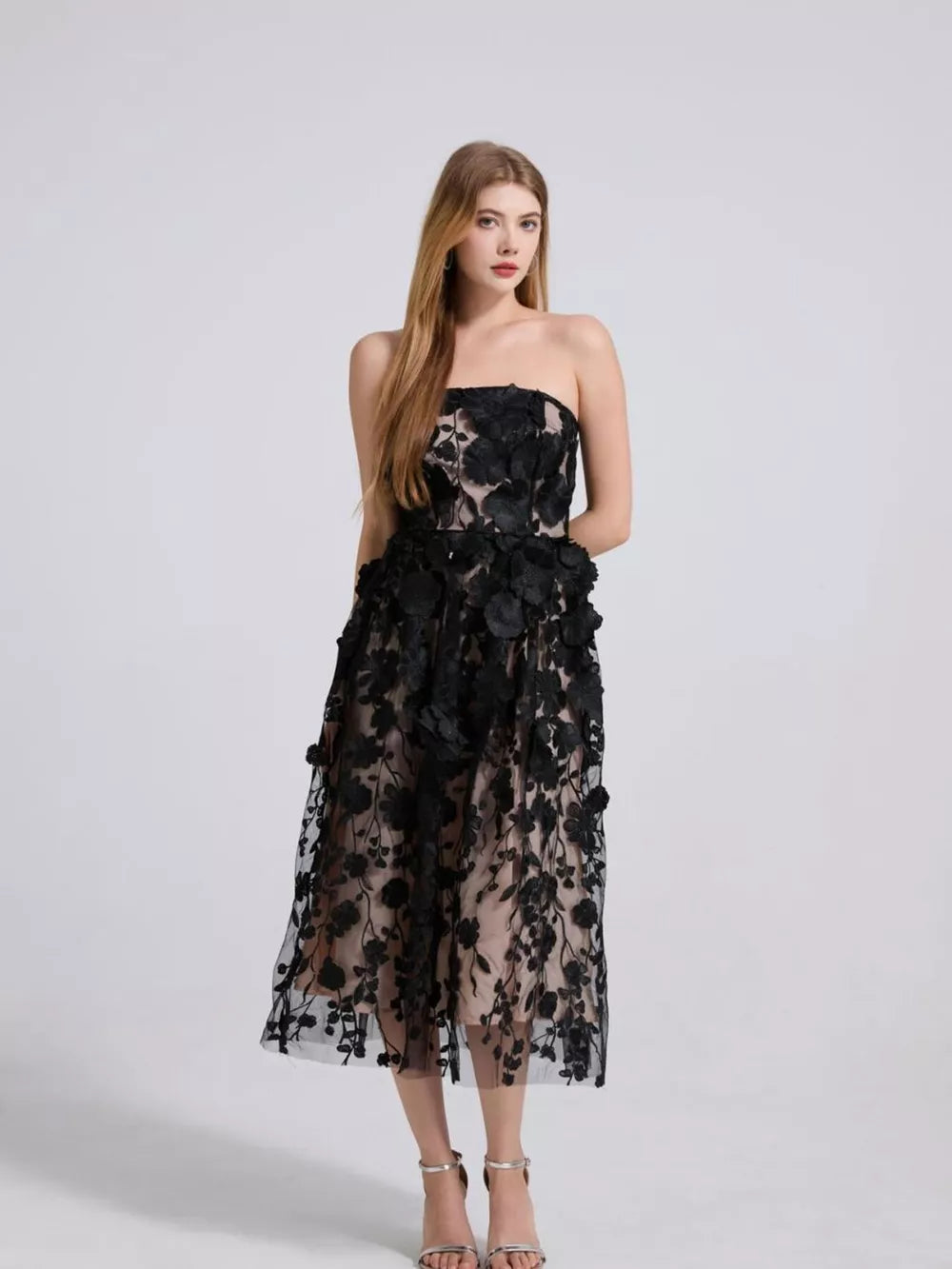 Black strapless midi dress with intricate floral applique and sheer overlay.