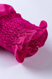 Cerise playsuit with shirred blouson sleeves and ruffled cuffs.