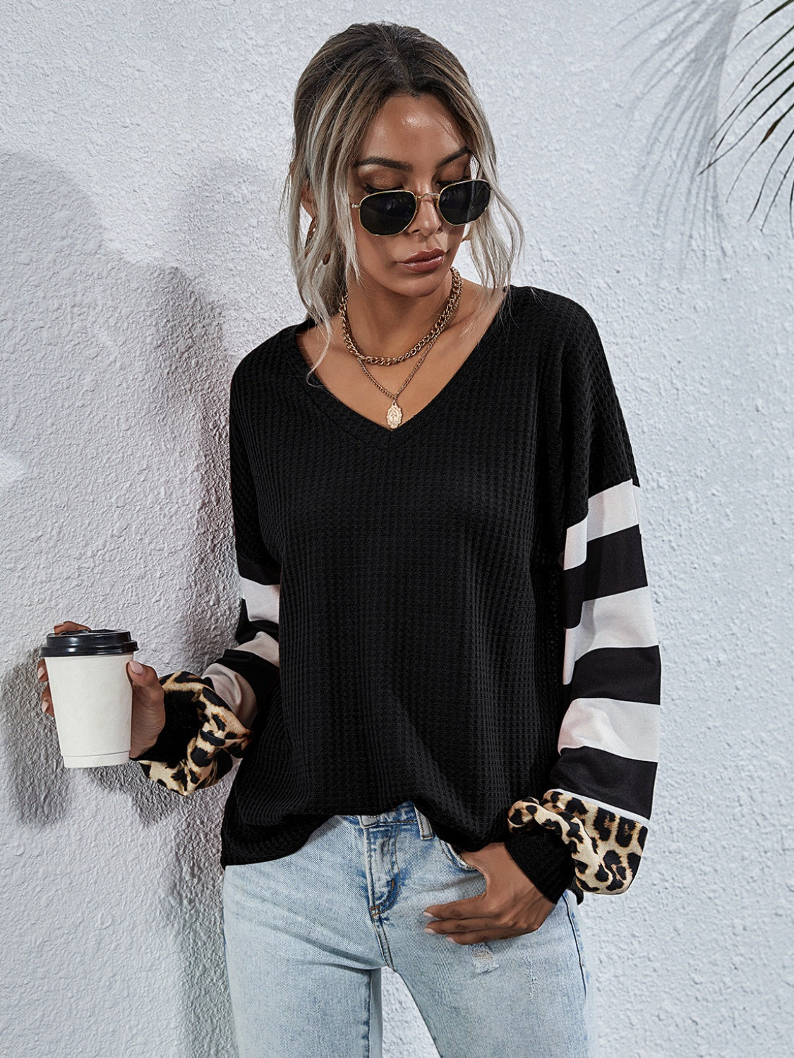 Black waffle knit top with striped and leopard print sleeves.