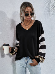 Black waffle knit top with striped and leopard print sleeves.