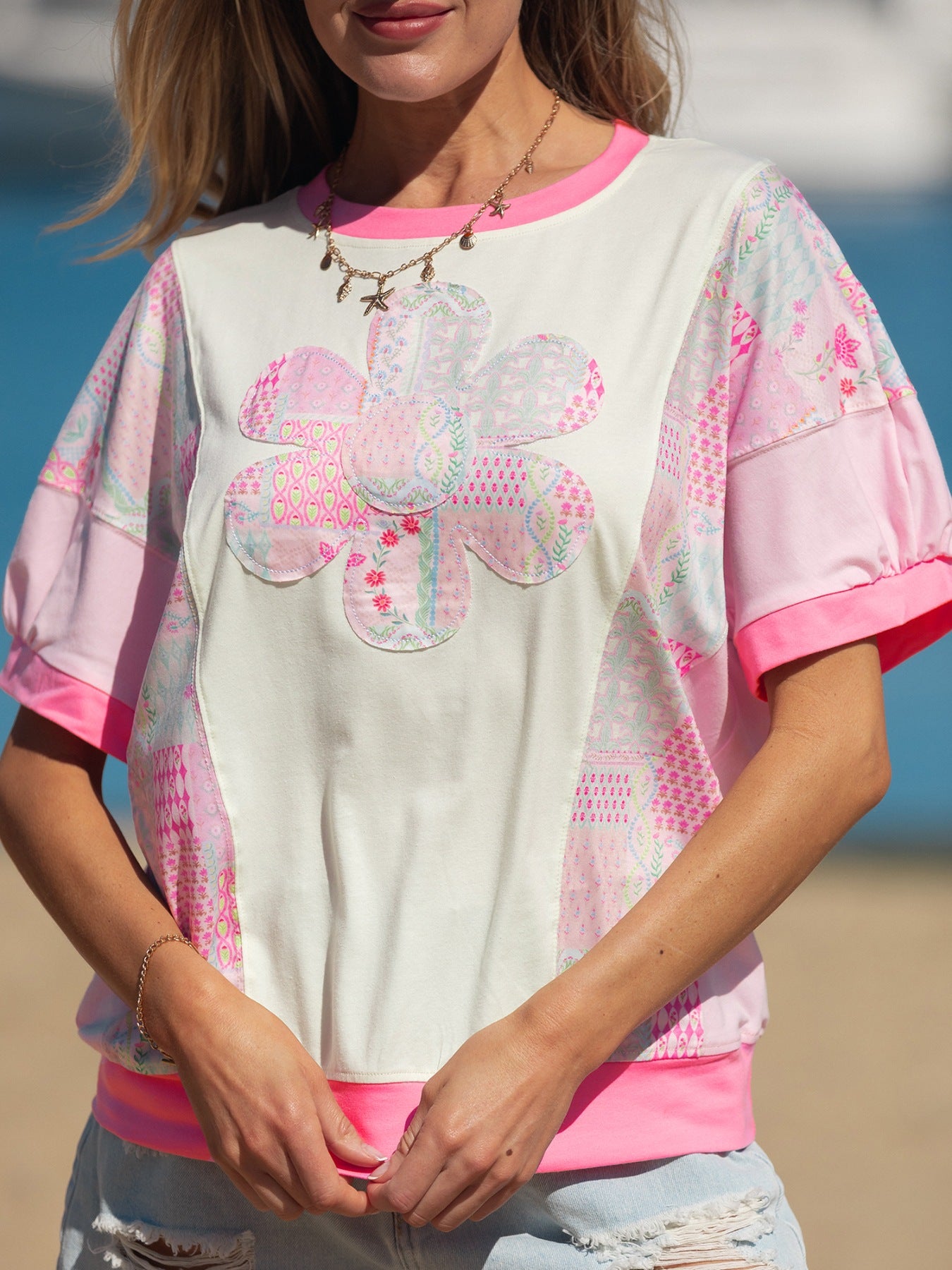 Maternity t-shirt with floral patchwork, crew neck, short sleeves, and pink trim.