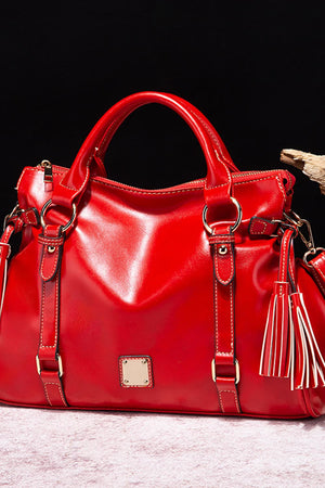 Red structured satchel bag with tassel detail and gold hardware.