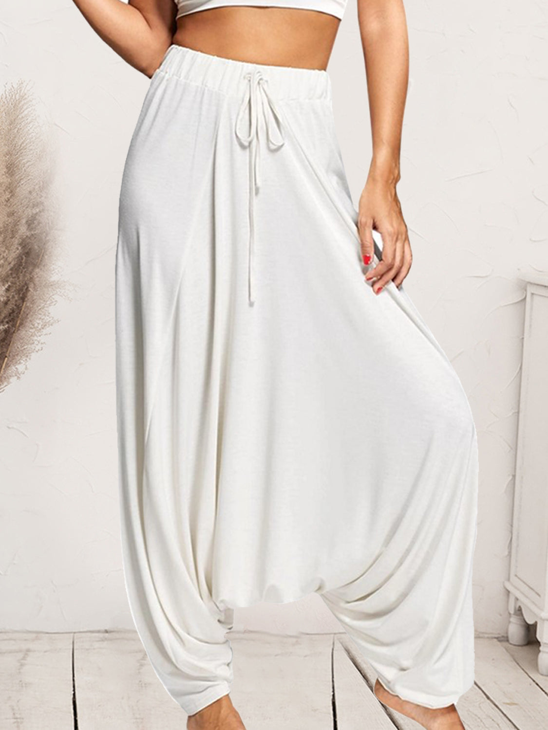 White drape-front drawstring harem pants with a relaxed fit.