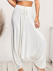 White drape-front drawstring harem pants with a relaxed fit.